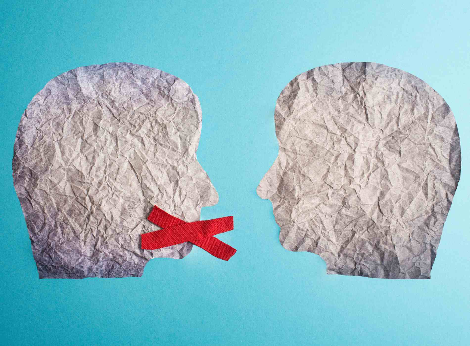 Two silhouette faces look at each other, one has a red cross over his mouth, censorship free speechGerm