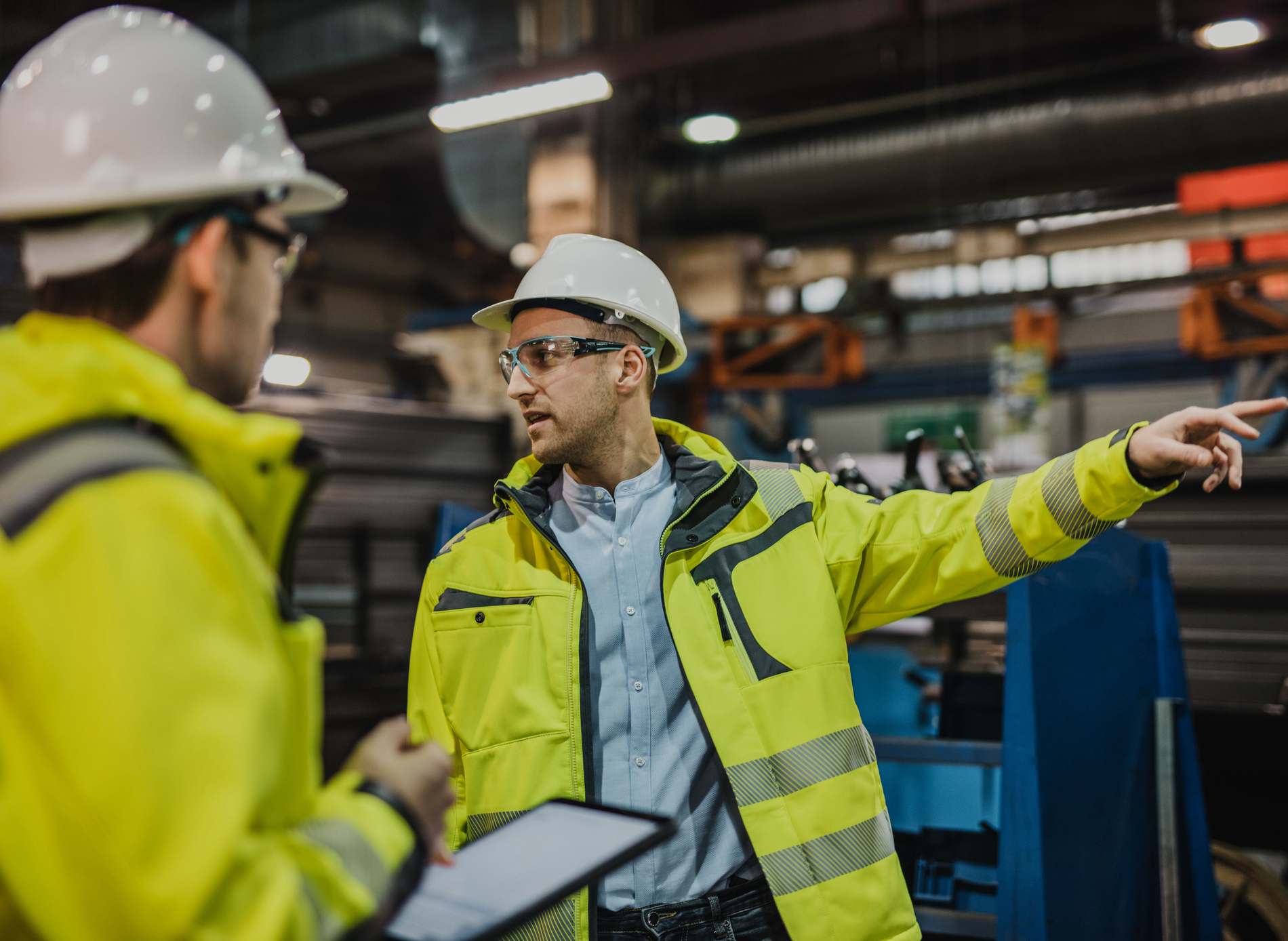 Young male Engineer explaining work to his worker in factory.