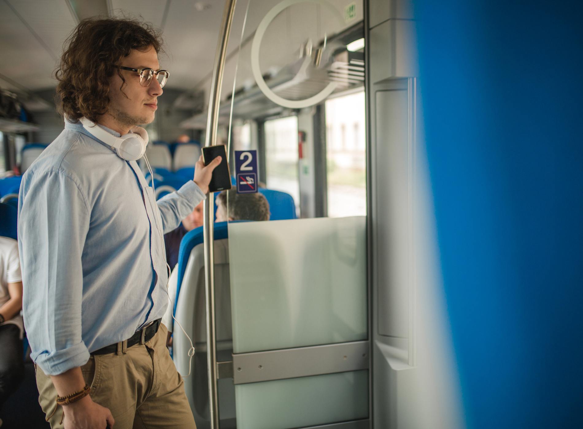 Young businessman traveling with train, standing and waiting for the next station