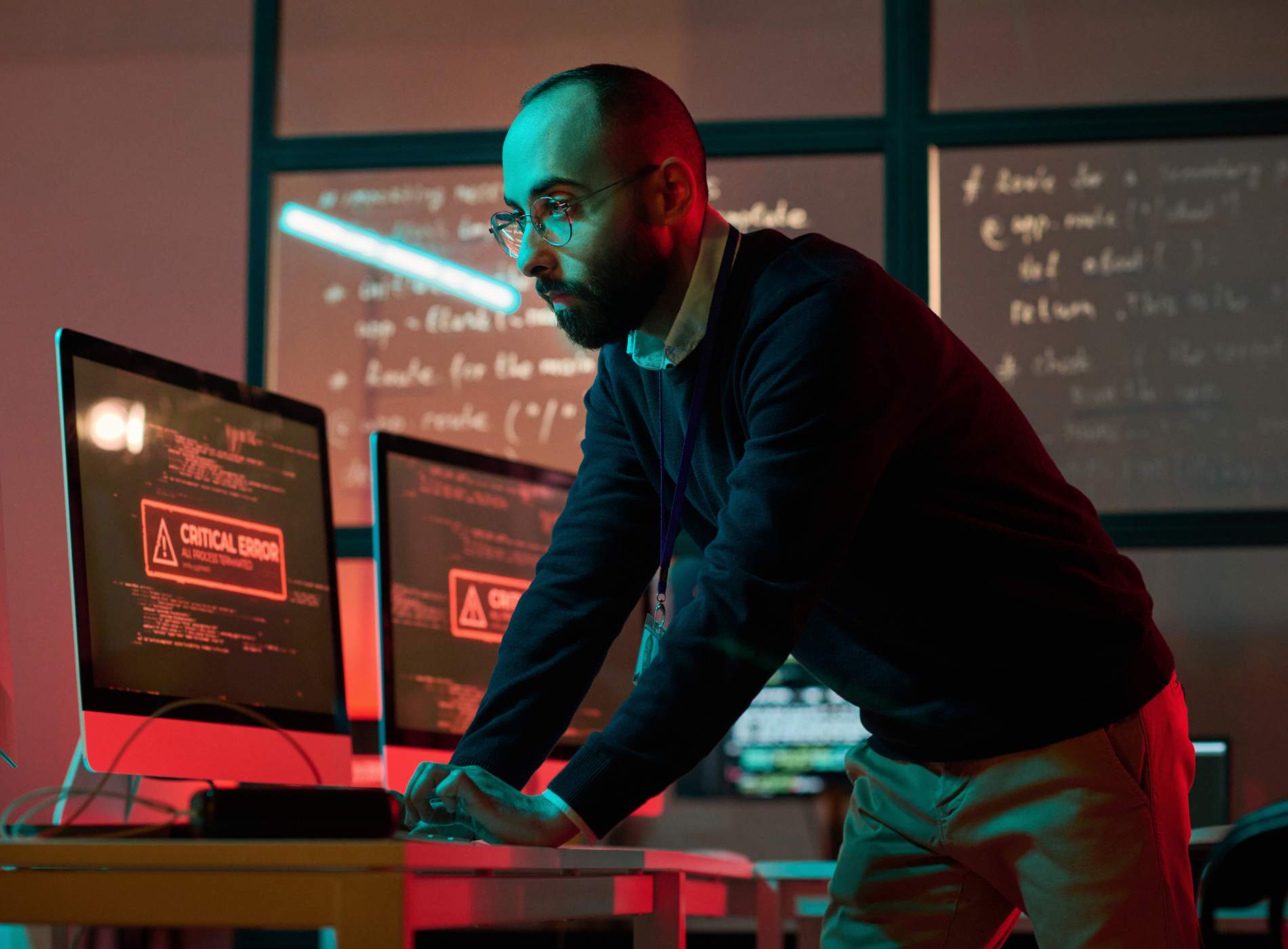 Dramatic portrait of bearded cybersecurity expert preventing emergency and using computer with red critical error message