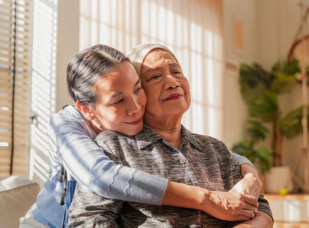 Asian Family, old woman hugging her daughter and cancer with sad people on a sofa in the home living room during recovery. Love, trust or comfort with a sick senior female parent embracing Daughter and sick mother hugging