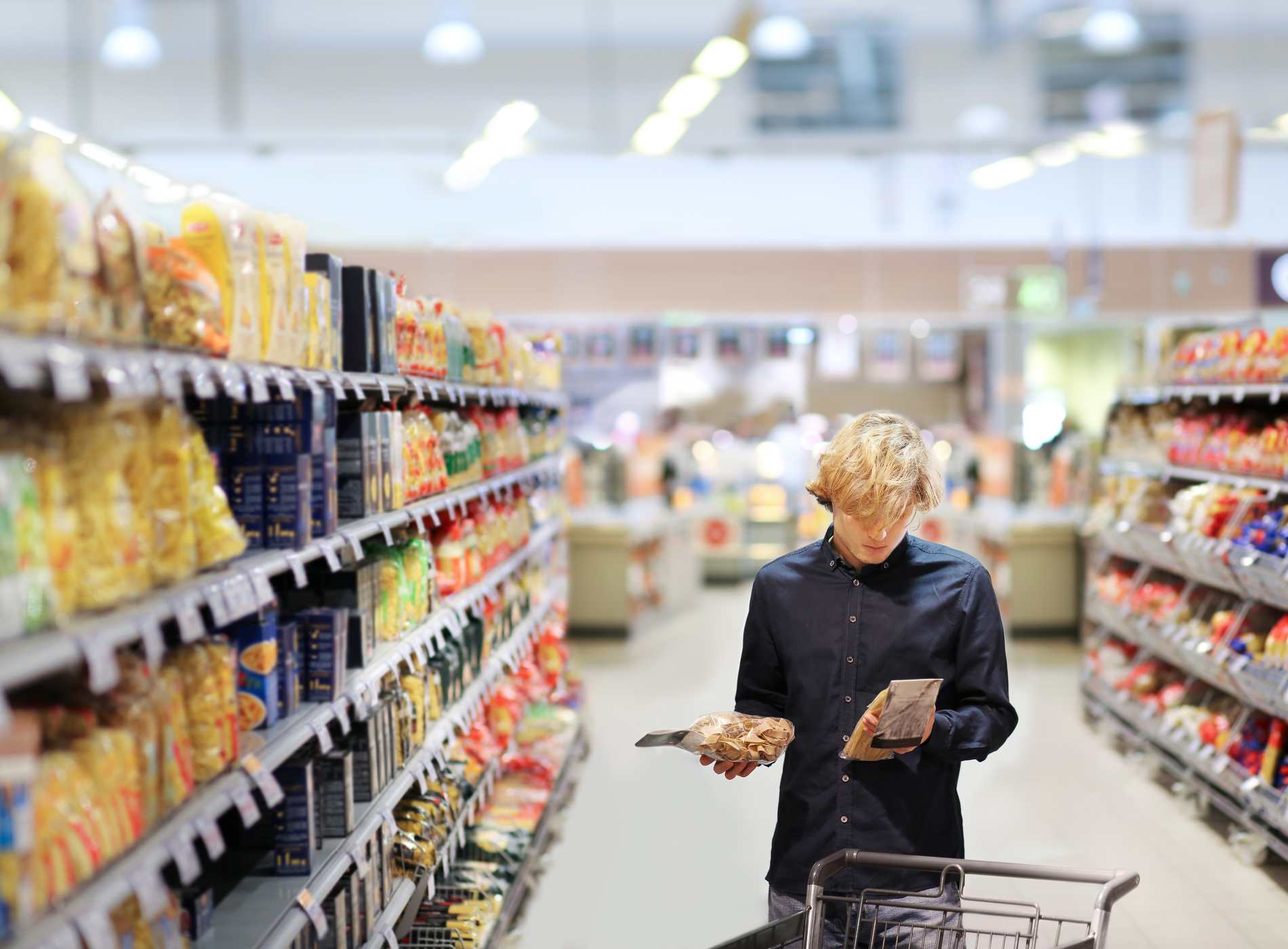 Man shopping in supermarket, reading product information