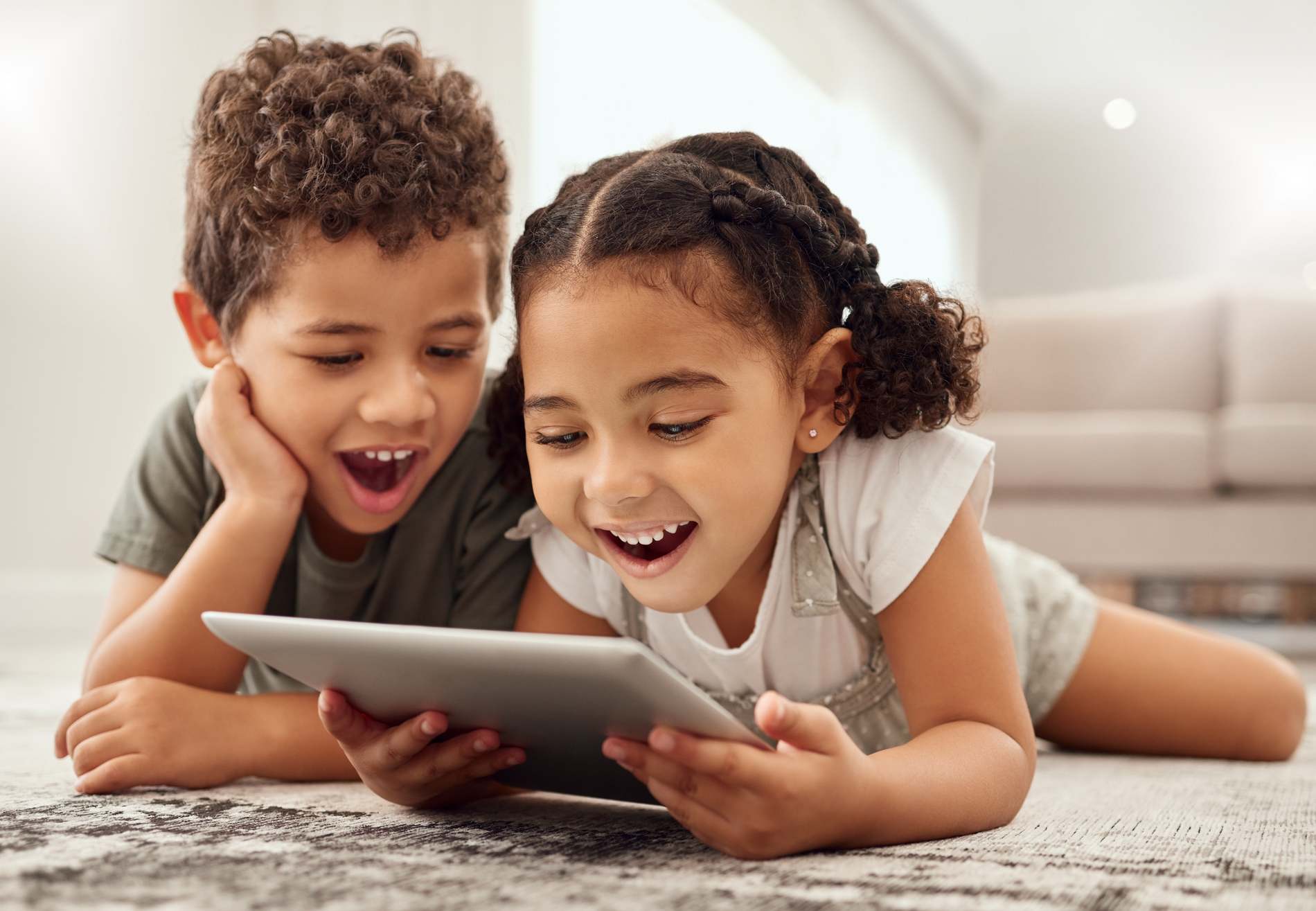 Tablet, children and family with a brother and sister watching movies on a living room floor together. Internet, kids and technology with a girl and boy streaming online subscription service at home
