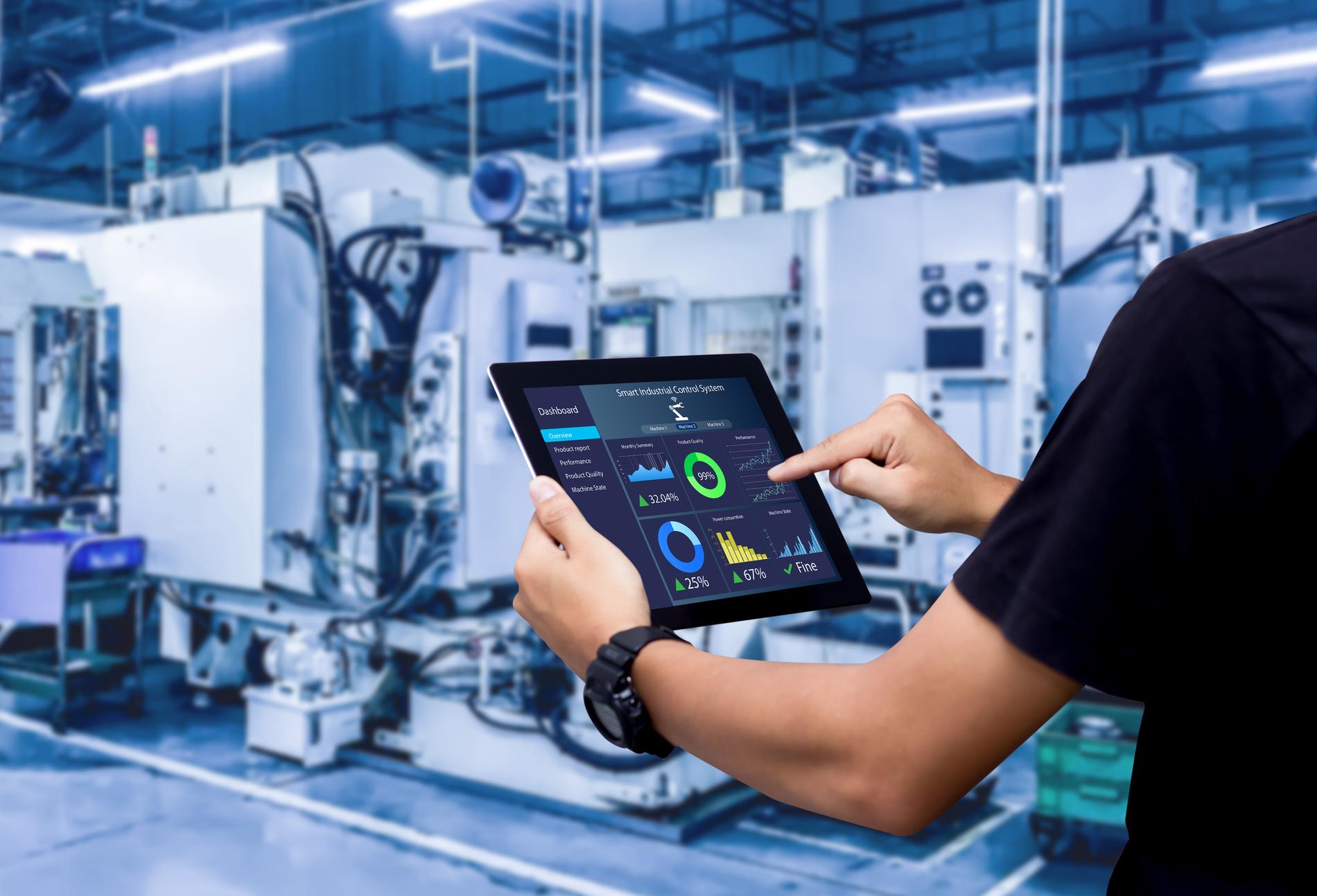 Smart industry control concept.Hands holding tablet on blurred automation machine as background