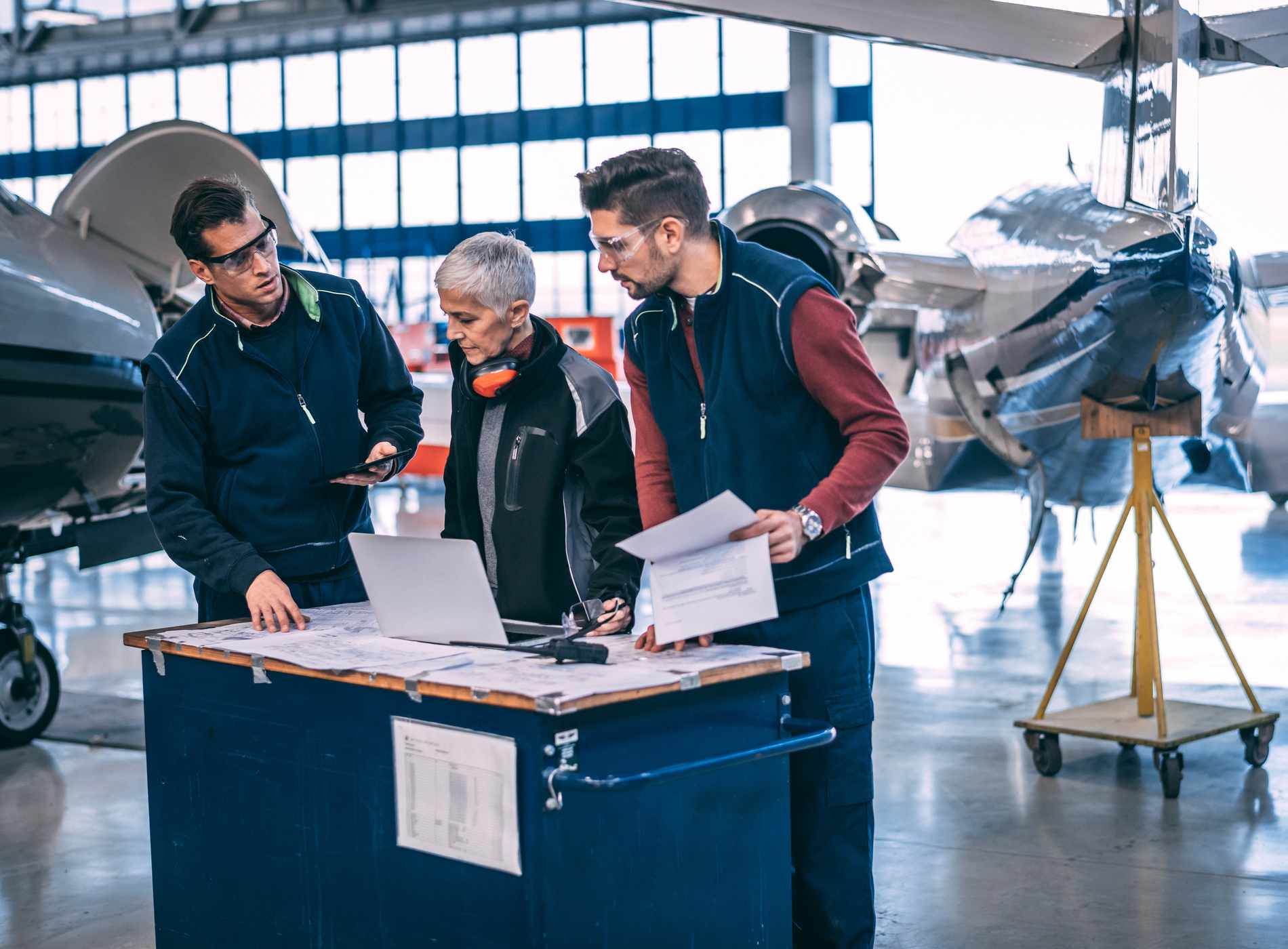 Aircraft engineer crew coordinating together in an aircraft hangar.