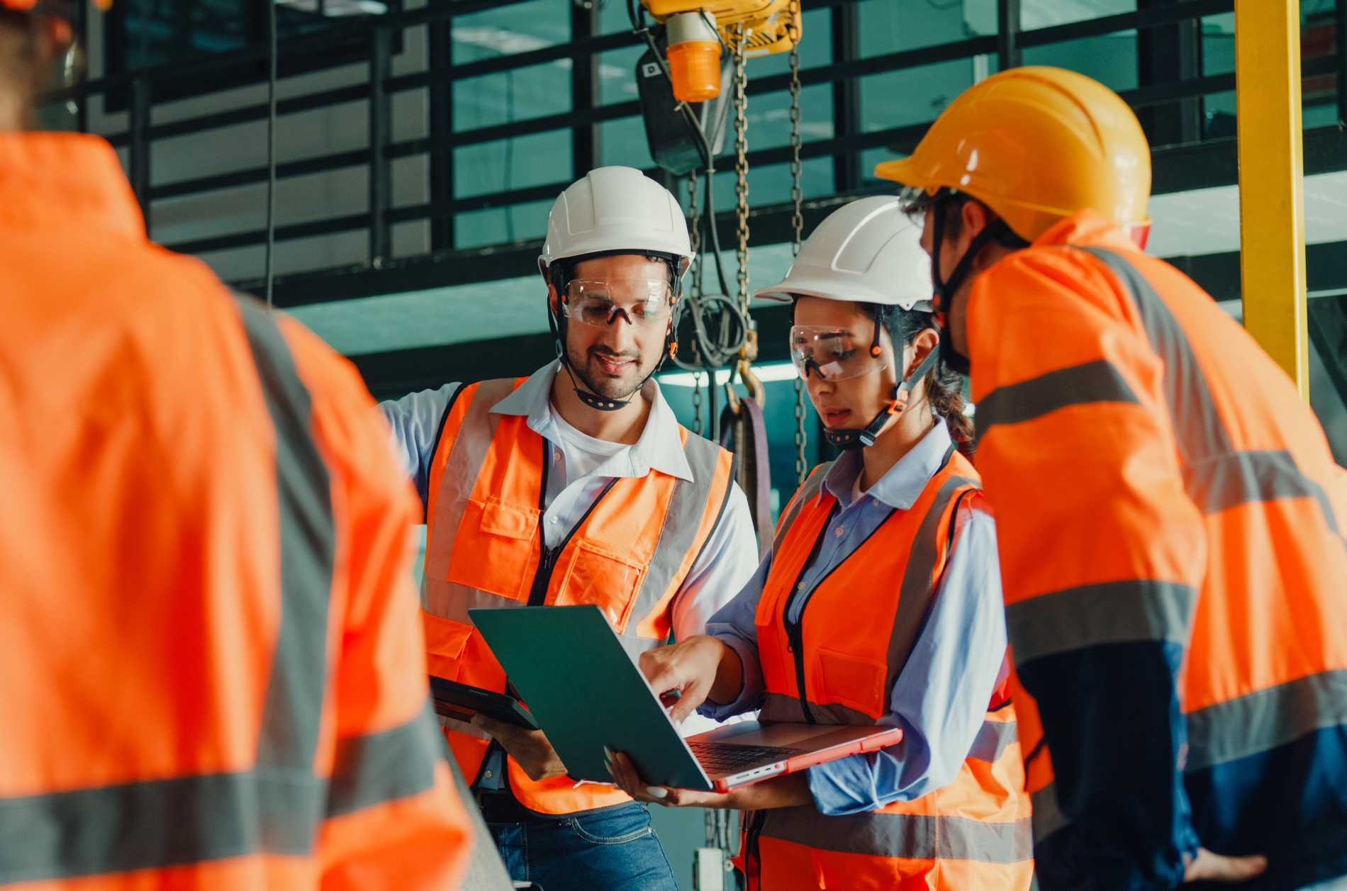 Team of industrial engineers meeting analyze machinery blueprints consult project on laptop in manufacturing factory. Engineering and sustainable production plant concept.