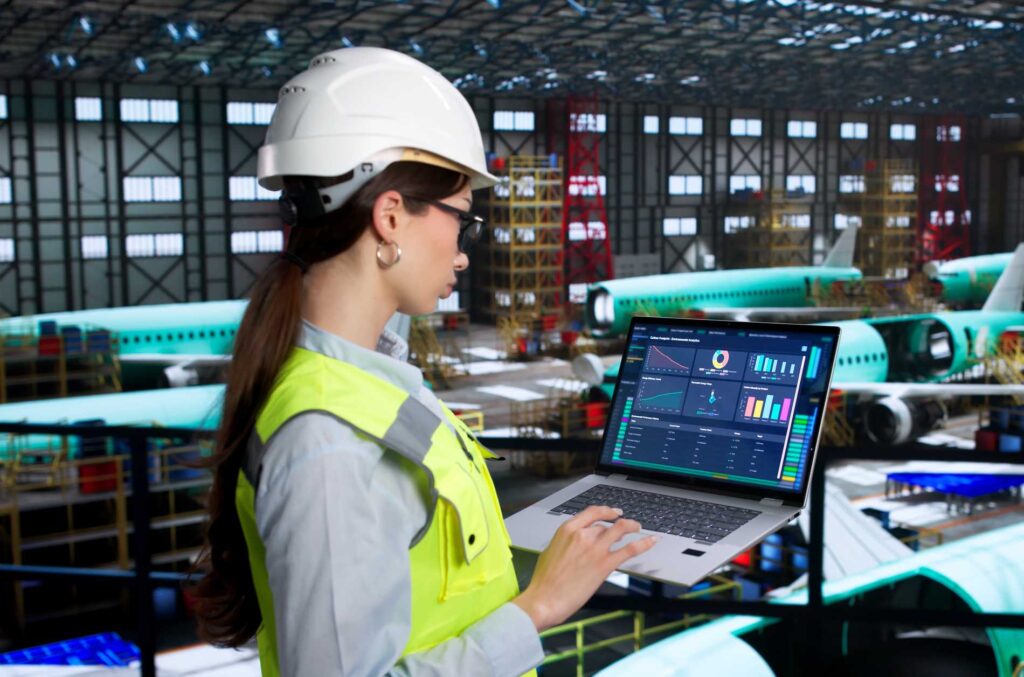 Young Female Engineer Inspects Aircraft Systems Using Laptop In Factory.