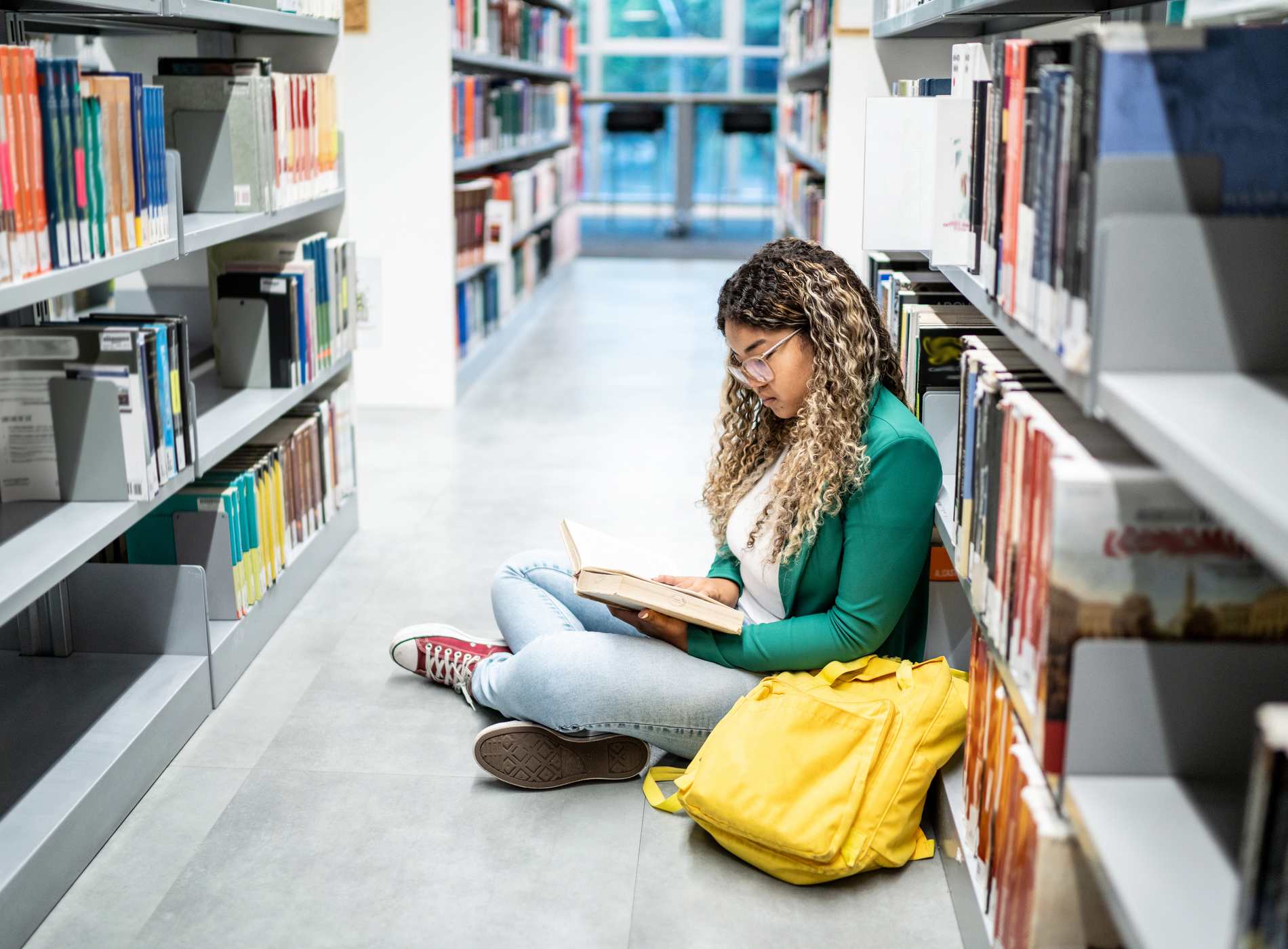 Young student woman sitting on ground at the university library