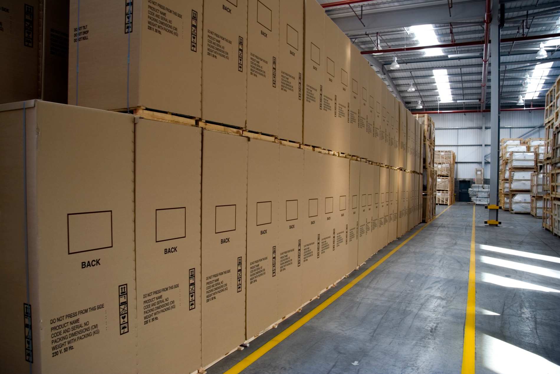 Closeup of crates stacked in newly built warehouse with fire exit escape lines on floor