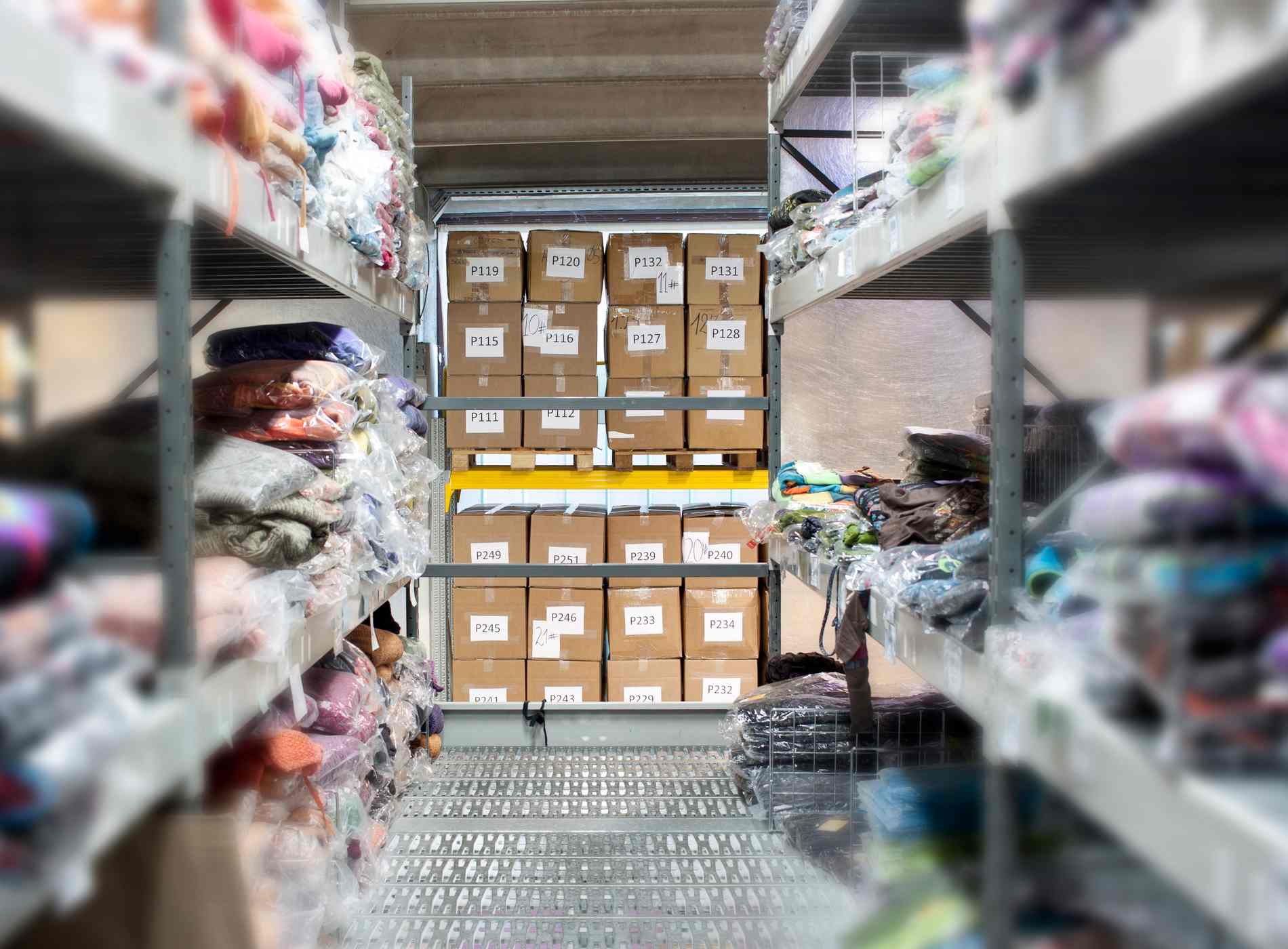 A part of wholesaling warehouse with clothes on the shelves and stored numbered boxes.
