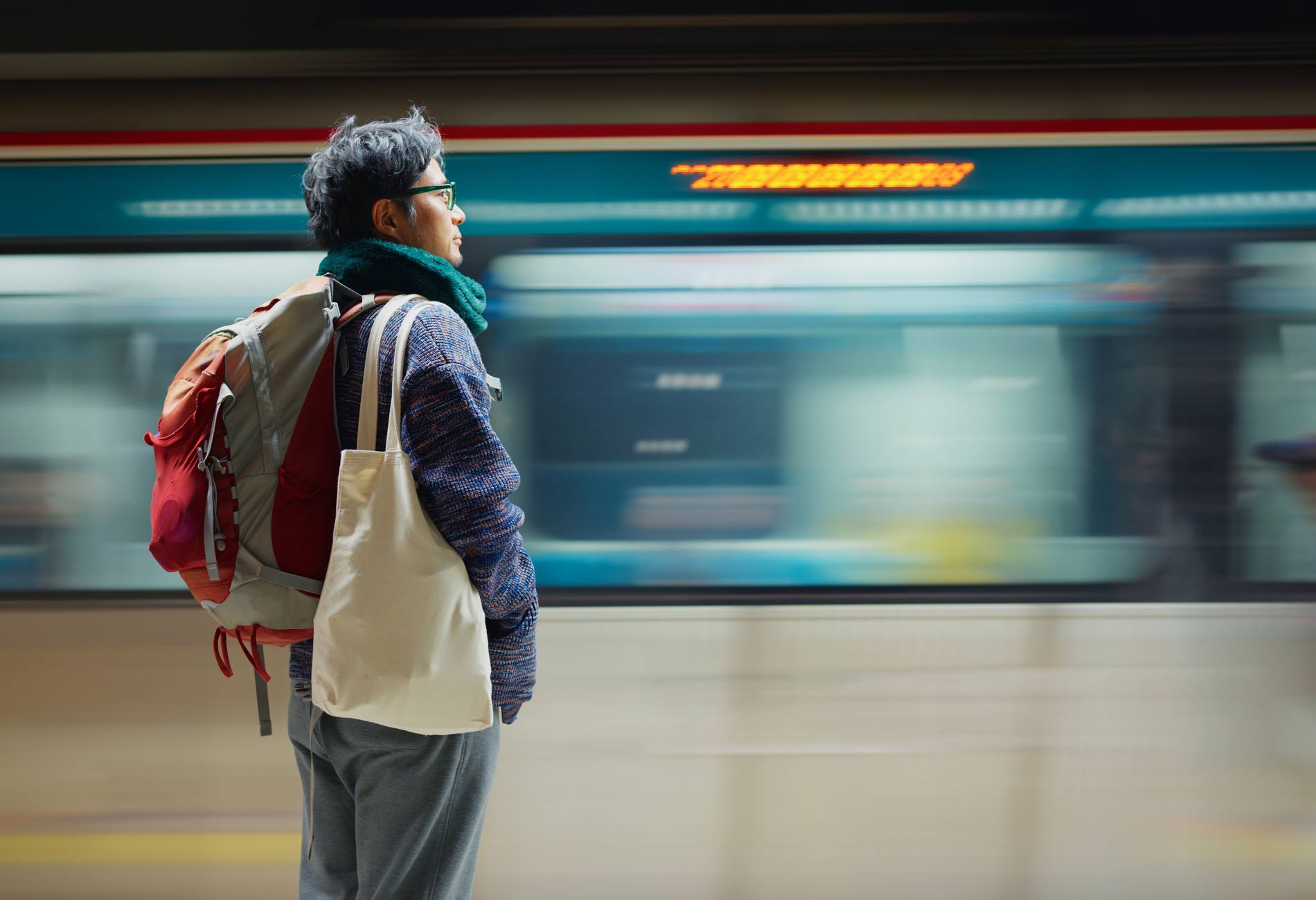 A man solo tourist is waiting the train to arrive at the station. He uses the public transportation to explore the city.